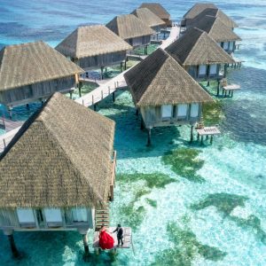 Stunning aerial view of overwater bungalows in Fuvahmulah, Maldives, with crystal clear waters.