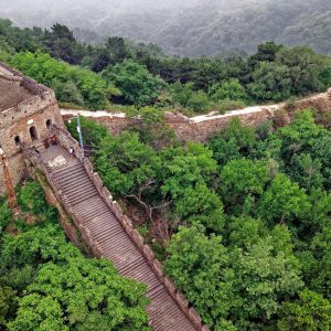 Drone shot of the Great Wall of China amidst lush greenery in Huairou, Beijing.