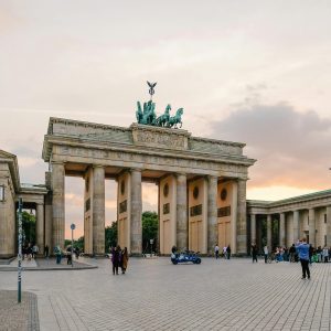 Scenic view of Berlin's Brandenburg Gate with people gathering at sunset.