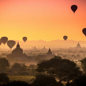 Captivating view of hot air balloons floating over ancient temples in Bagan, Myanmar at sunrise.