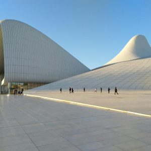 Striking modern architecture of the Heydar Aliyev Center in Baku with people walking under clear skies.